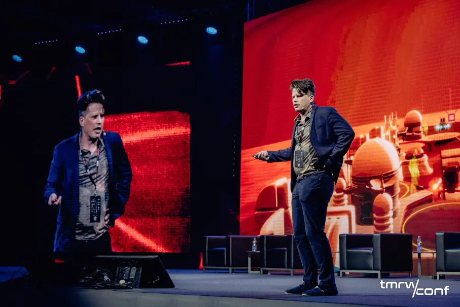 Two speakers on the red-lit main stage