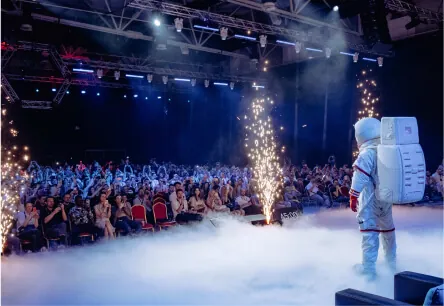 The TMRW astronaut mascot on stage with pyrotechnics